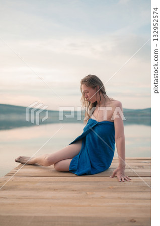 Woman in Blue Towel Sitting on Dock 132952574