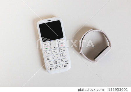 Close up of of a retro push-button telephone and a fitness bracelet concept top view Close up of of a retro push-button telephone and a fitness bracelet concept top view 132953001