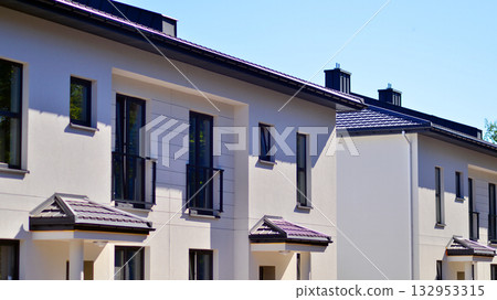 New single family houses in a new development area. Residential homes with modern facade. Terraced family homes in newly developed housing estate. The real estate market in the suburbs.  132953315
