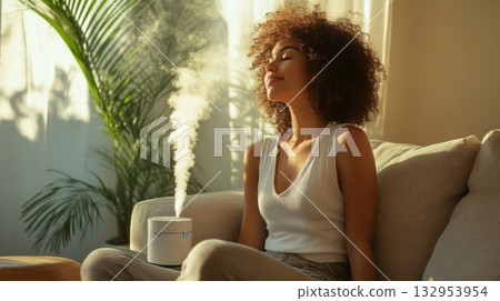 woman relaxing on sofa with essential oil diffuser 132953954