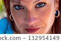 Young woman with striking green eyes and freckles enjoys sunny day in outdoor setting 132954149