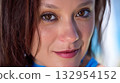 Close-up of a woman with brown eyes, showcasing natural beauty and bright expression in a sunny setting 132954152