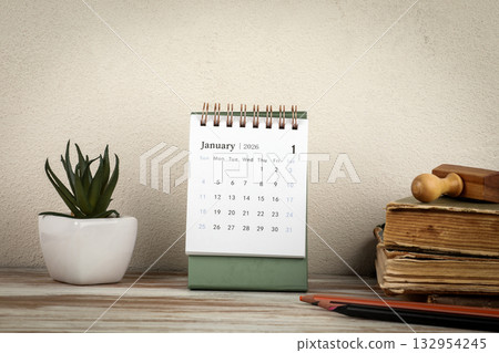 January 2026 Calendar on Wooden Desk. Vintage books, pencils and a small plant on a wooden surface 132954245