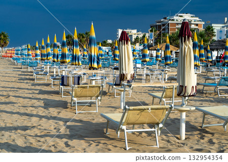 Sun loungers on sandy beach with Umbrellas. Empty seaside resort. Italy. Sun loungers on sandy beach with Umbrellas. Empty seaside resort. Italy. 132954354