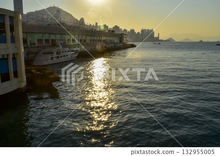 The seascape at sunset with ships and cityscape in the background. Sun-rays reflected on the calm sea. Sea background and cityscape. Nature concept. The seascape at sunset with ships and cityscape in the background. Sun-rays reflected on the calm sea. Sea background and cityscape. Nature concept. 132955005