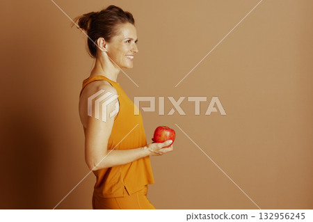 Woman in Orange Activewear with Apple Woman in Orange Activewear with Apple 132956245