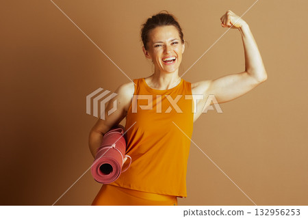 Strong Woman Flexing Bicep with Yoga Mat 132956253