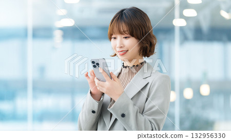 使用智慧型手機的微笑的女人/女商人 132956330