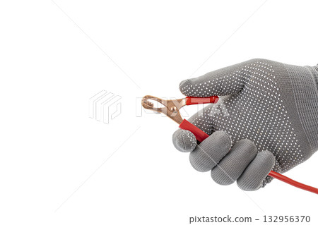 Gloved Hand Holding Red Alligator Clip Wire Against White Background: Highlighting Electrical Connection Tool and Glove Texture Gloved Hand Holding Red Alligator Clip Wire Against White Background: Highlighting Electrical Connection Tool and Glove Texture 132956370