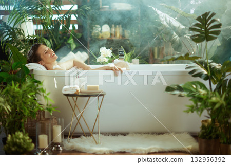 Smiling Woman Enjoying a Steamy, Luxurious Bubble Bath 132956392