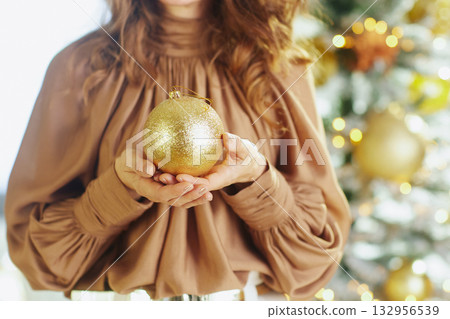 Woman with Gold Ornament by a Festive Tree 132956539