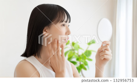 一個女人在鏡子裡檢查她的皮膚 一個女人在鏡子裡檢查她的皮膚 132956753