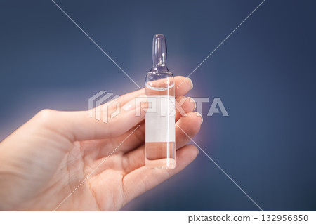Woman's hand holds clear glass medicine ampoule Woman's hand holds clear glass medicine ampoule 132956850