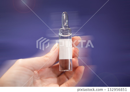 Woman's hand holds clear glass medicine ampoule Woman's hand holds clear glass medicine ampoule 132956851