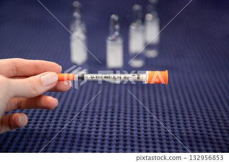 Woman holds insulin syringe medical background blurred Woman holds insulin syringe medical background blurred 132956853
