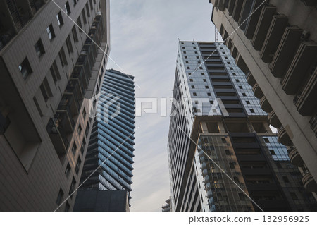 Skyscrapers tower over a narrow street under cloudy skies. High quality photo 132956925