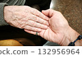 A man and an elderly man hold hands. The scene is warm, comforting, and reflects love and understanding. 132956964