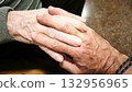 A man and an elderly man hold hands. The scene is warm, comforting, and reflects love and understanding. 132956965