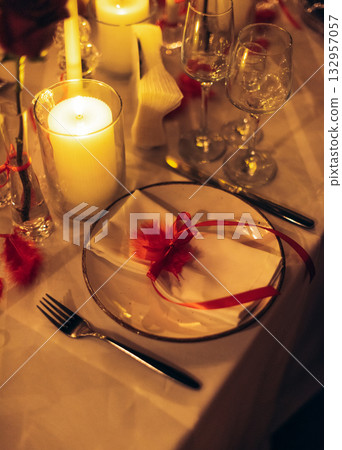 Warm candlelit banquet table with roses and crystal decor in restaurant Warm candlelit banquet table with roses and crystal decor in restaurant 132957057