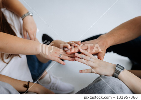 Young friends stacking hands showing unity and support on light background Young friends stacking hands showing unity and support on light background 132957366