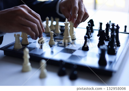 Businessman wearing suit, playing chess, game of strategy, leadership and management concept. Businessman wearing suit, playing chess, game of strategy, leadership and management concept. 132958006