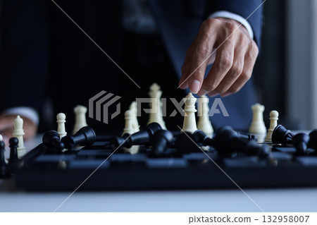 Businessman wearing suit, playing chess, game of strategy, leadership and management concept. Businessman wearing suit, playing chess, game of strategy, leadership and management concept. 132958007