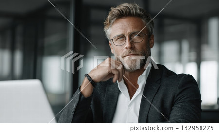 man is seated at a white desk in a modern office 132958275