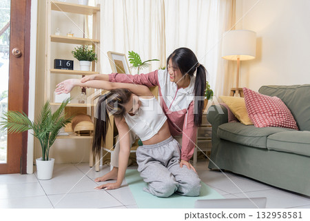 Young women workout yoga active teen teaching friend exercising sport, showing proper form for side bend stretch, enjoying active lifestyle for better health and wellness indoors. 132958581