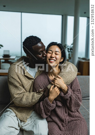 Couple happily sharing a kiss in a bright modern home with Scandinavian design Couple happily sharing a kiss in a bright modern home with Scandinavian design 132958632