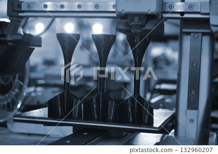 Shank stabilizer printing on 3D printer from molten plastic on desktop of 3d printer. Plastic stabilization tail creating on 3D printer. Black prototype model of rocket bomb tip printing on 3D printer 132960207