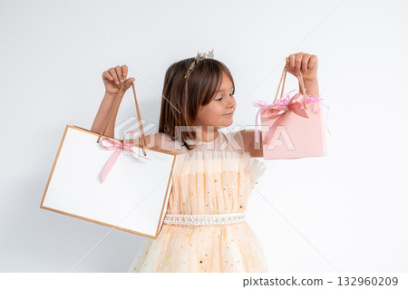 Young caucasian girl in dress holding gift bags with ribbons Young caucasian girl in dress holding gift bags with ribbons 132960209