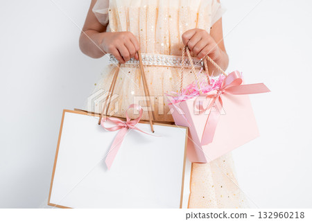 Caucasian young female in elegant dress holding pink and white gift bags with ribbons Caucasian young female in elegant dress holding pink and white gift bags with ribbons 132960218