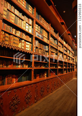An atmospheric vintage library with carved wooden bookshelves and rows of antique books in Porto, Portugal. A concept for lovers of literature, fantasy, and dark, academic interiors. 132960818
