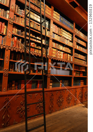 An atmospheric vintage library with carved wooden bookshelves and rows of antique books in Porto, Portugal. A concept for lovers of literature, fantasy, and dark, academic interiors. An atmospheric vintage library with carved wooden bookshelves and rows of antique books in Porto, Portugal. A concept for lovers of literature, fantasy, and dark, academic interiors. 132960819