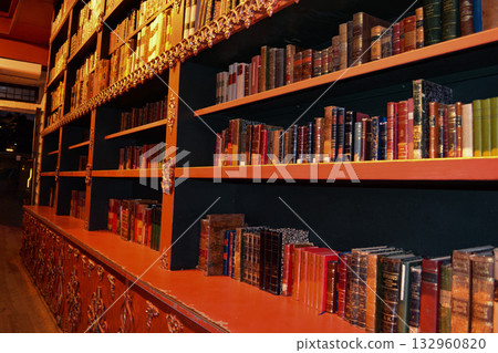 An atmospheric vintage library with carved wooden bookshelves and rows of antique books in Porto, Portugal. A concept for lovers of literature, fantasy, and dark, academic interiors. 132960820