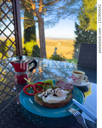 Outdoor breakfast scene with poached egg toast salad salami red pepper rings and espresso on a patio Outdoor breakfast scene with poached egg toast salad salami red pepper rings and espresso on a patio 132960842