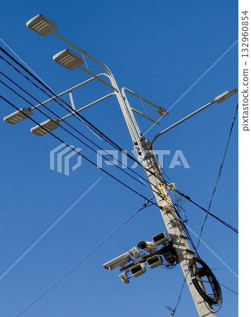 Modern street light pole with multiple fixtures and cables against blue sky 132960854