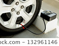 Car tire being inflated with portable air compressor and pressure gauge. Auto service and safety concept. 132961146