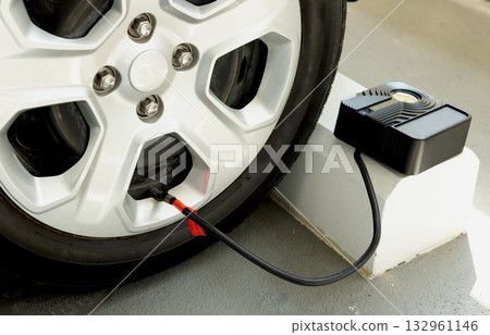 Car tire being inflated with portable air compressor and pressure gauge. Auto service and safety concept. 132961146