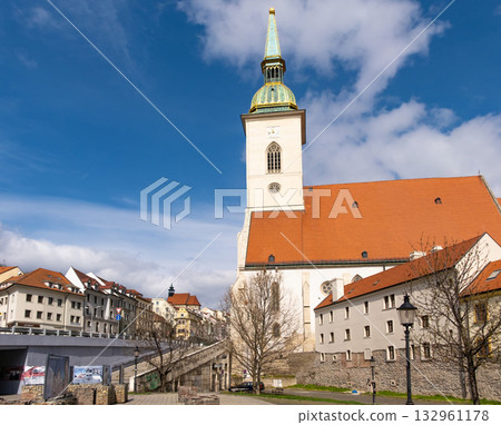 St. Martin's Cathedral stands prominently against the Bratislava skyline, showcasing its historical architecture. Nearby buildings and a clear sky add to the urban landscape's charm St. Martin's Cathedral stands prominently against the Bratislava skyline, showcasing its historical architecture. Nearby buildings and a clear sky add to the urban landscape's charm 132961178