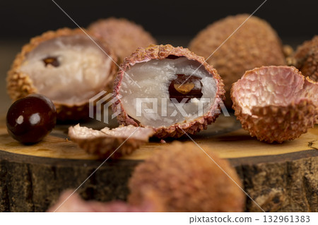 open red lychees cut into pieces on a wooden table, ripe lychee fruits with cut pink tough peel, cooking lychee open red lychees cut into pieces on a wooden table, ripe lychee fruits with cut pink tough peel, cooking lychee 132961383