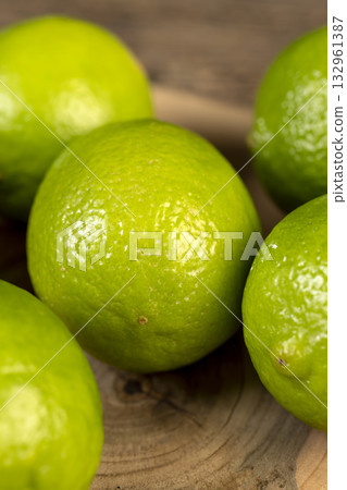 green citrus limes scattered on a wooden table in the kitchen, ripe and juicy lime fruits for cooking both sauces and drinks and other food 132961387