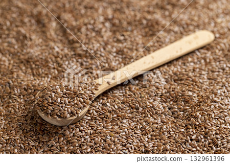 flax for sowing in a wooden spoon, a large number of brown flax seeds and a wooden spoon with seeds flax for sowing in a wooden spoon, a large number of brown flax seeds and a wooden spoon with seeds 132961396