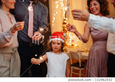 Family members holding sparklers during Christmas celebration. Family members holding sparklers during Christmas celebration. 132962032