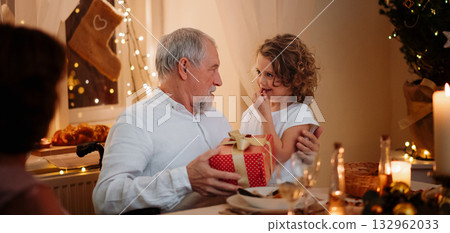 Grandfather spending Christmas Eve with small granddaughter. Grandfather spending Christmas Eve with small granddaughter. 132962033