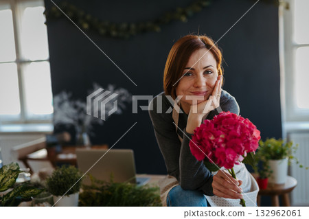 Smiling female florist working in her small flower shop. Smiling female florist working in her small flower shop. 132962061
