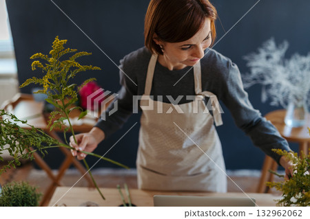 Female florist working in her small flower shop. Female florist working in her small flower shop. 132962062
