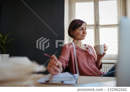 Female designer having coffee break during work. 132962082