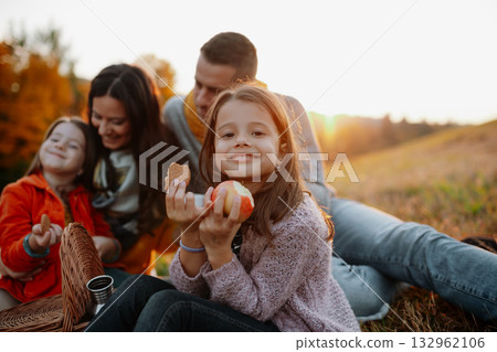 Parents with young children sitting outdoors in autumn light. 132962106