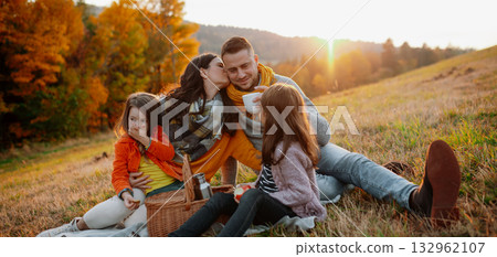 Parents with young children sitting outdoors in autumn light. 132962107